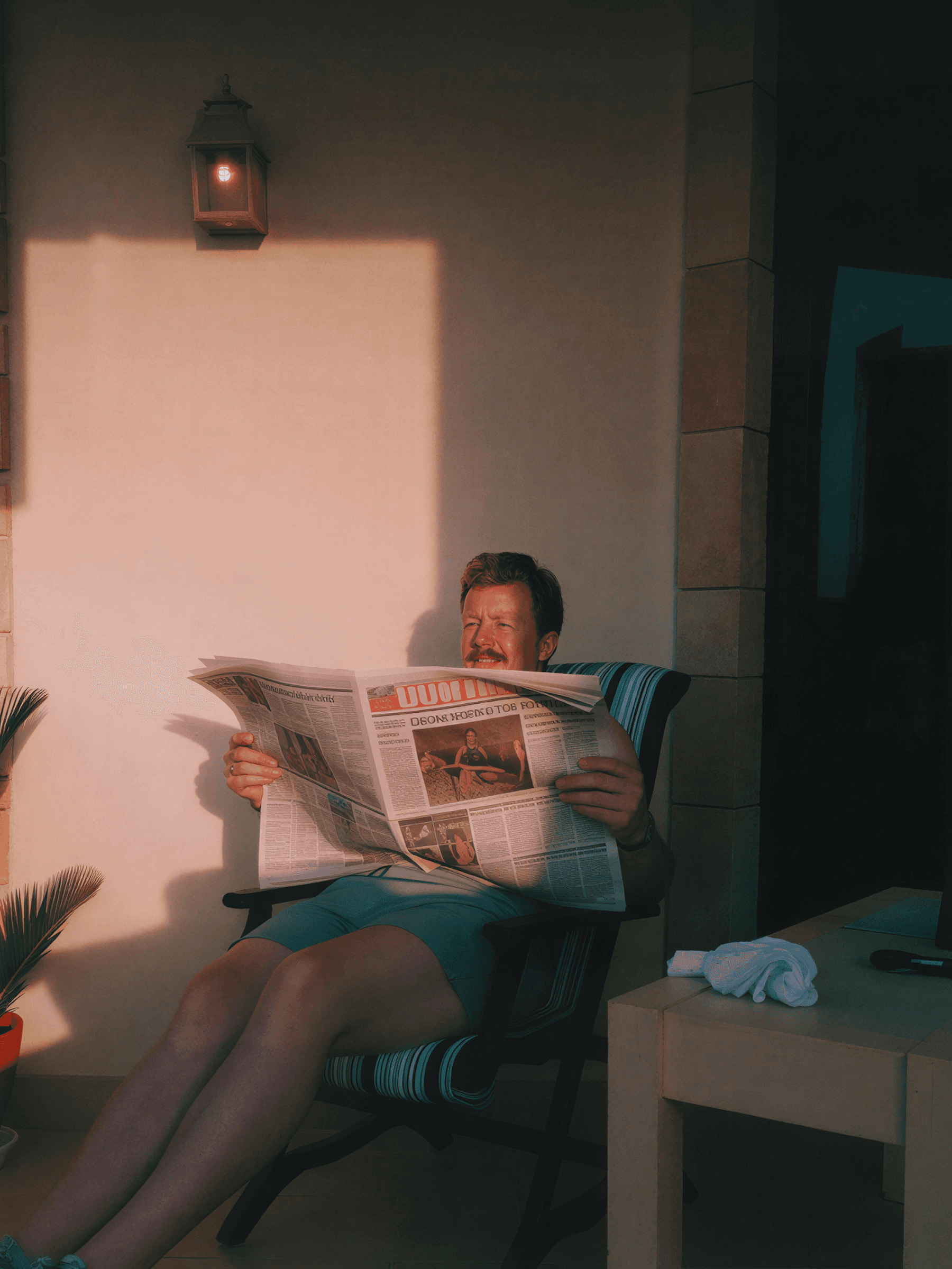 A person reading a newspaper in warm light